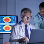 AI Beats Doctors in Harvard ER Study, Showing Major Shift in Healthcare Male surgeon and doctor working at laptop in hospital conference room